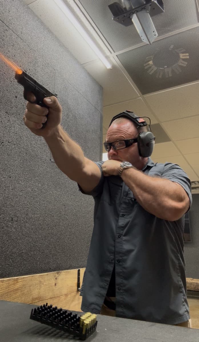 Instructor firing at the range with muzzle flash
